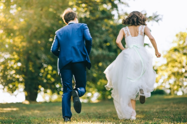 Amorosa pareja cogidos de la mano con anillos contra el vestido de novia