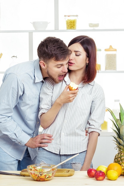 Amorosa pareja feliz comiendo una manzana en la cocina