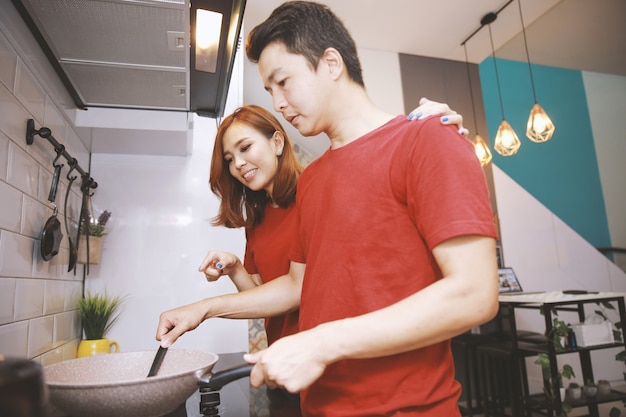 Amorosa pareja joven alegre hablando y cocinando juntos divirtiéndose en la cocina