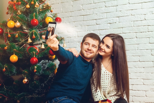 Amorosa pareja joven haciendo selfie de Navidad. Año nuevo. Humor navideño.