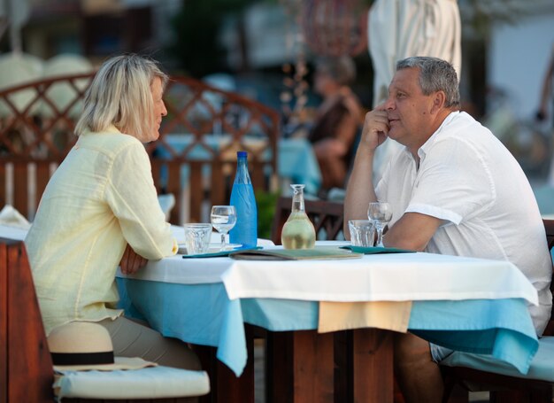 Amorosa pareja madura cenando en la cafetería al aire libre