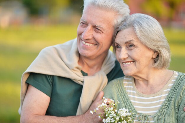 Amorosa pareja madura en el parque de verano con flores.