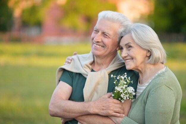 Amorosa pareja madura en el parque de verano con flores.