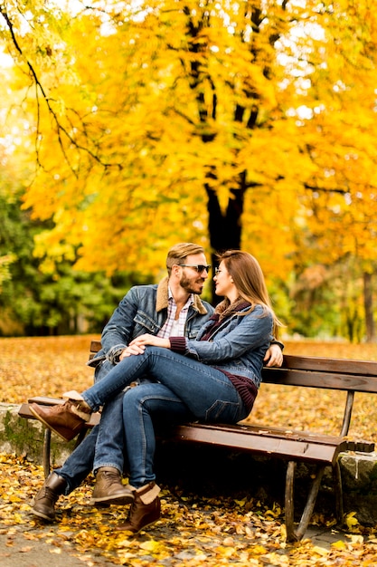 Amorosa pareja sentada en el banco en el parque de otoño