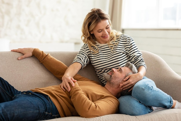 Amoroso casal de meia idade relaxando no sofá em casa