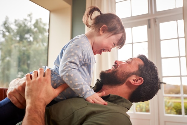 Amoroso padre jugando con la risa de la hija con síndrome de Down en casa juntos