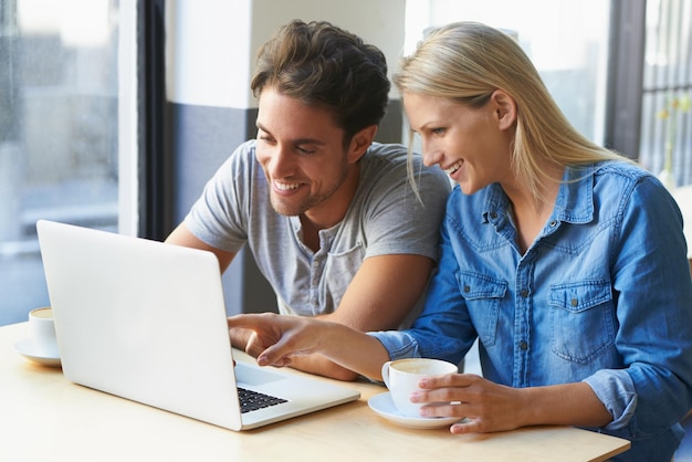 Amoroso wifi gratis Captura recortada de una pareja joven usando una computadora portátil en un café