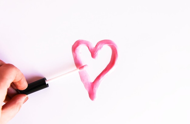 Amostra desenhada de coração de brilho labial rosa em um fundo branco.