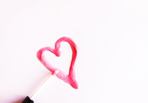 Amostra desenhada de coração de brilho labial rosa em um fundo branco.