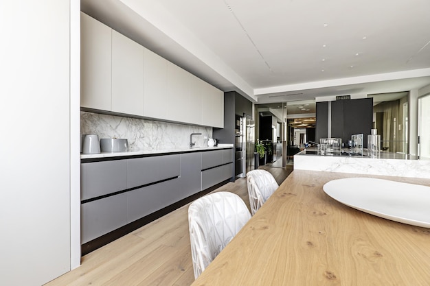 Amplia cocina con muebles en gris y blanco de estilo minimalista y gran isla central de mármol y madera
