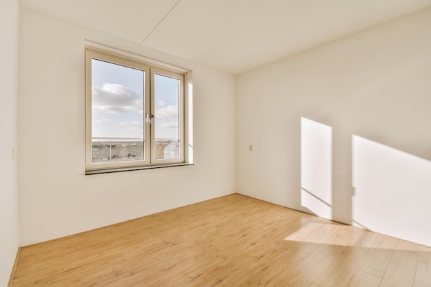 Amplia habitación vacía con suelos de parquet y una gran ventana en una casa moderna