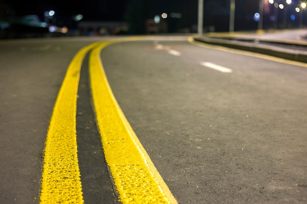 Amplia línea de señalización de marcado amarillo brillante a lo largo de la moderna carretera de asfalto vacía lisa y ancha que se extiende hasta el horizonte