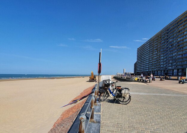 Amplia playa de arena cerca del mar con muchas casas y hotel. La gente sentada en la playa en el día soleado de verano.