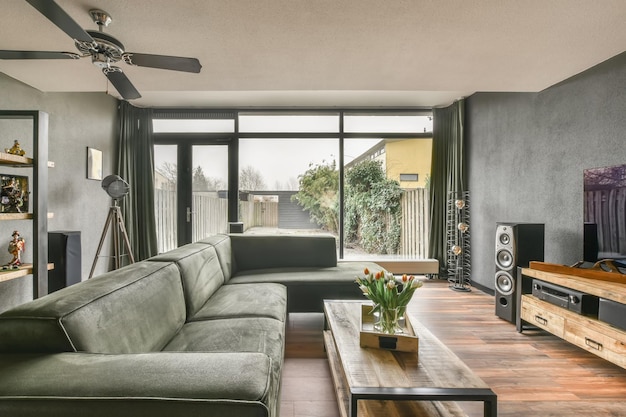 Amplia sala de estar con pisos de madera y un gran sofá verde con acceso al patio trasero.