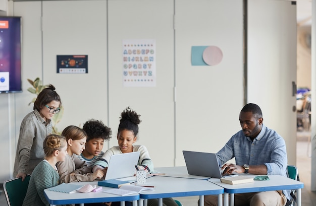 Amplio ángulo de visión de estudiantes y profesores trabajando juntos en el aula moderna