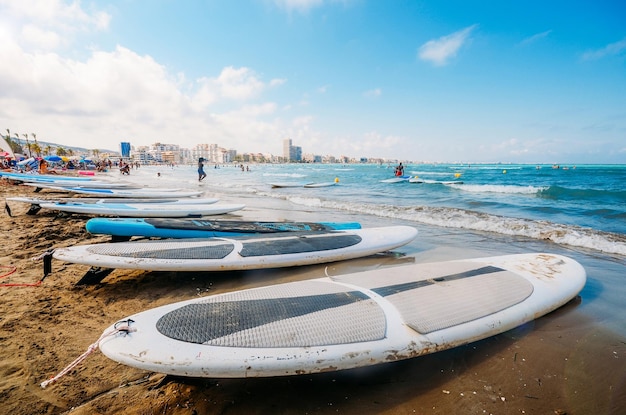 Amplio ángulo de visión de las tablas de surf en primer plano con los turistas en la popular Platja Nord Mar Mediterráneo Castellón España