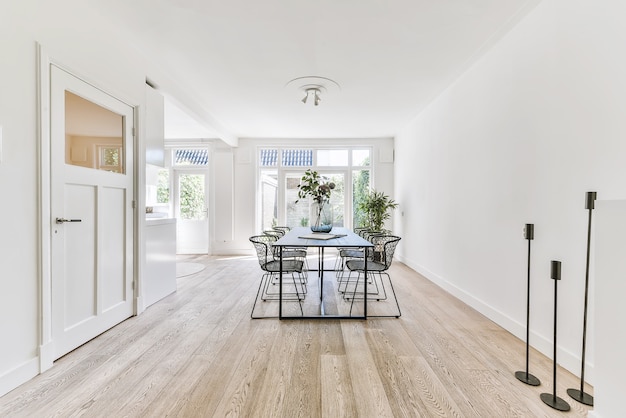 Amplio comedor de estilo minimalista con mesa y sillas en un apartamento moderno con paredes blancas y piso de madera