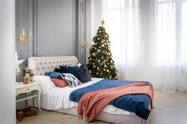 Un amplio dormitorio de luz blanca en estilo loft con un árbol de Navidad decorado y una guirnalda.