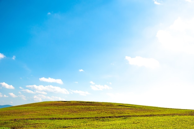 Amplo campo verde em colinas e céu azul com nuvens