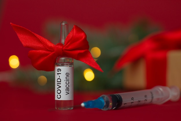 Ampola da vacina COVID-19 perto da árvore de Natal