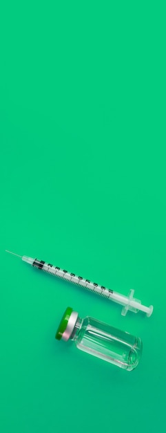 Ampola de seringa com medicamento no fundo verde do panorama