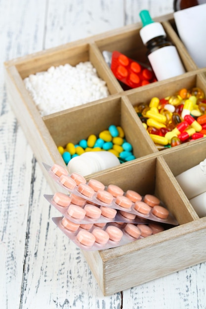 Foto ampolas de pílulas médicas em caixa de madeira em fundo colorido