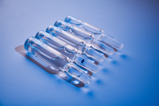 ampolas de vidro de medicamento em uma superfície azul close-up