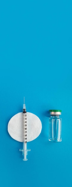 Ampolla de jeringa con medicamento sobre fondo azul panorama