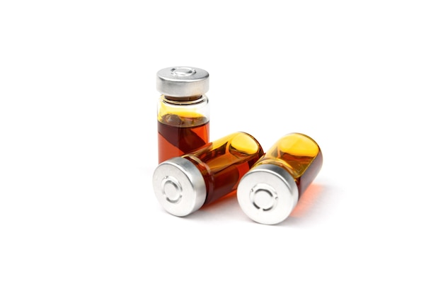 Ampolla médica de vidrio con la cápsula y el aceite en el interior aislado en blanco