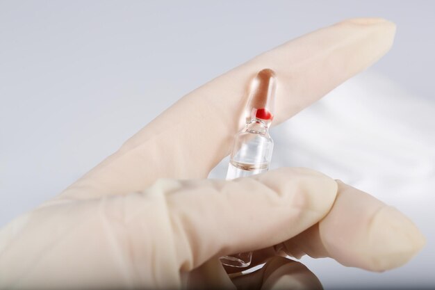 Foto ampolla de vidrio con medicamentos en la mano de la enfermera.