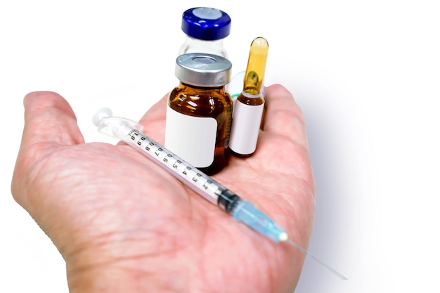 Ampollas de 3 ml y vial de fármaco con jeringa de plástico colocada en una aguja médica a mano aislada sobre fondo blanco