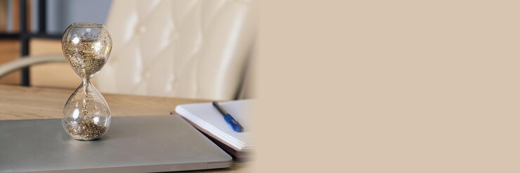 Ampulheta de vidro fica em um laptop em um conceito de mesa de passar o tempo