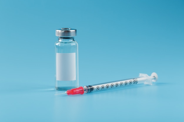 Ampulle mit einem Impfstoff und einer Spritze für Viren und Krankheiten auf blauem Grund.