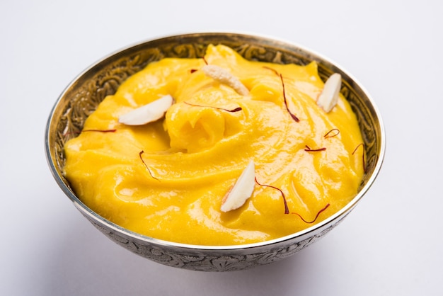 Amrakhand es un yogur con sabor a Alfonso o Shrikhand, dulce popular indio servido con frutas secas y azafrán con mango entero, sobre un fondo colorido. enfoque selectivo