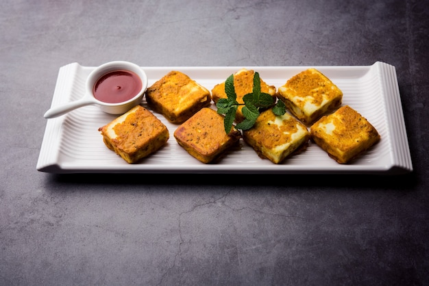 Amritsari Paneer Tikka feito com cubos de queijo cottage mergulhados em uma massa feita com besan, chat masala e especiarias e frito na frigideira, servido com ketchup