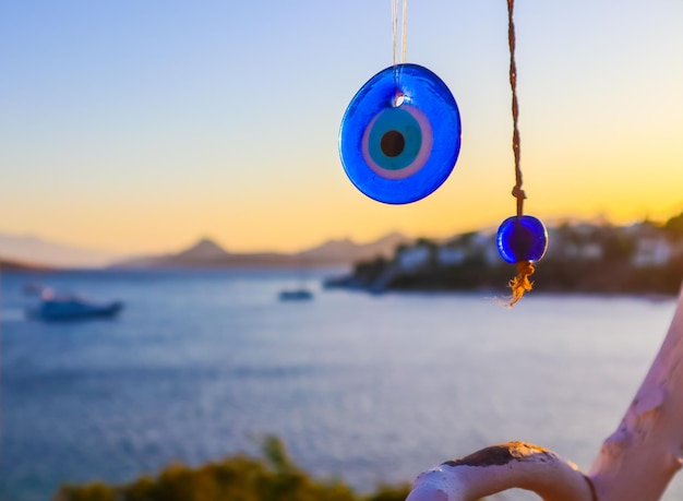 Amuleto de mal de ojo azul en el fondo de un hermoso paisaje marino al atardecer