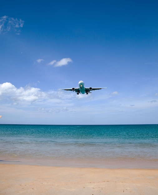 An einem sonnigen Tag landet ein Passagierflugzeug tief über dem Meer auf einem Flughafen in Strandnähe