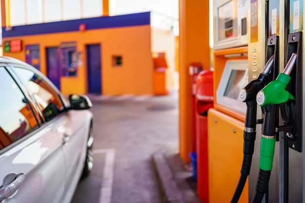 An einer Tankstelle geparktes Auto, das bereit ist, aus den Schläuchen zu tanken