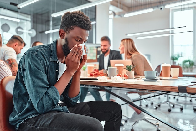 An Grippe erkrankter Mann, der im Büro arbeitet Hintergrund der Menschen