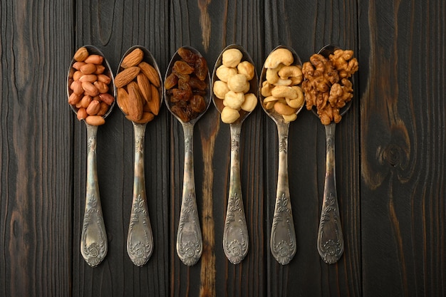 Anacardos de avellana pasas almendras cacahuetes nueces en cucharas de plata sobre un fondo rústico