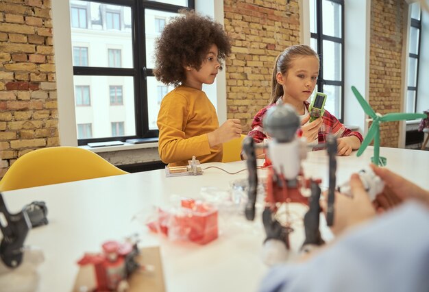 Análise lógica menino e menina fofos fazendo robôs durante a aula de tronco