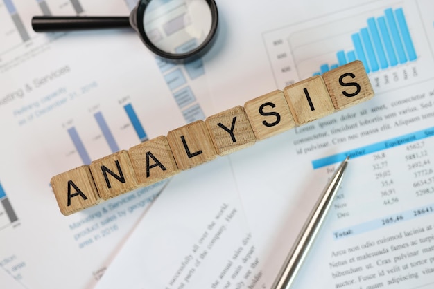 Foto análisis de palabras hecho de cubos de madera en documentos contables con estadísticas y bloques de gráficos con