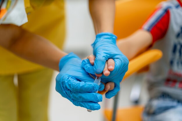 Análisis de sangre del dedo en un hospital. Enfoque selectivo en las manos del médico. La mano del niño en las manos del médico.