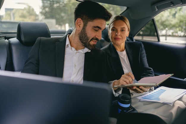 Analistas de negócios focados têm reuniões on-line usando laptop enquanto estão sentados nos assentos traseiros dos carros