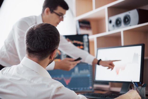 Analizando datos. Primer plano del equipo de jóvenes empresarios trabajando juntos en la oficina creativa mientras la mujer joven apunta a los datos presentados en el gráfico con lápiz.