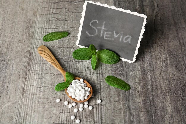 Analog von Würfelzucker und Stevia auf grauem Holzhintergrund