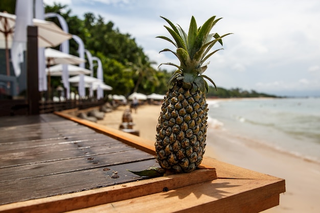 Ananas auf dem Holzschreibtisch am Sommerstrand.