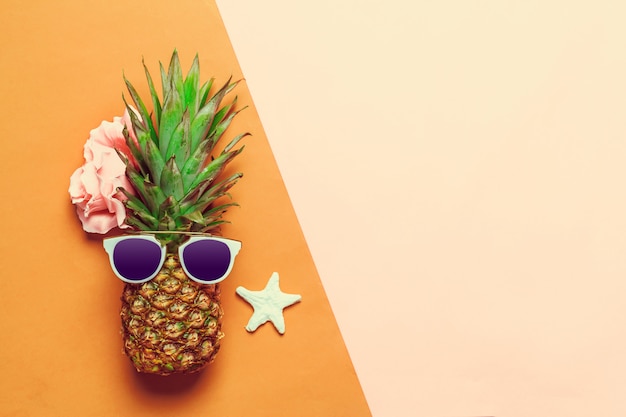 Ananas auf farbigem Papier mit Gläsern