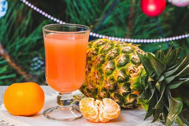 Ananas, ein Glas Saft und ein Tannenbaum mit Weihnachtsschmuck