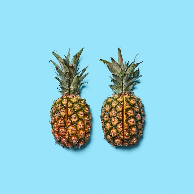 Ananas mit grünen Blättern in Stücke geschnitten auf blauem Hintergrund mit Platz für Text